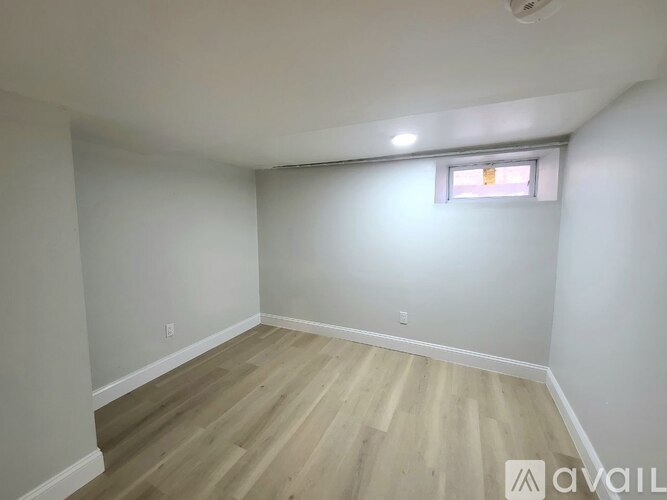 A room with wooden flooring and a window with blinds.