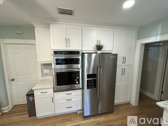 A kitchen with white cabinets and a stainless steel refrigerator.