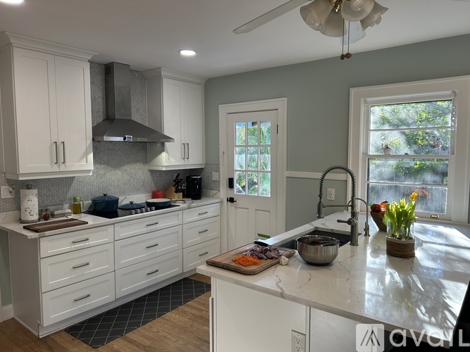 A kitchen with white cabinets and a marble countertop.