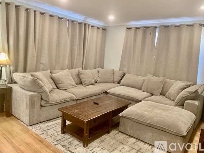 A living room with a large sectional sofa and a wooden coffee table.