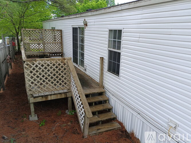 A white house with a wooden deck and stairs.