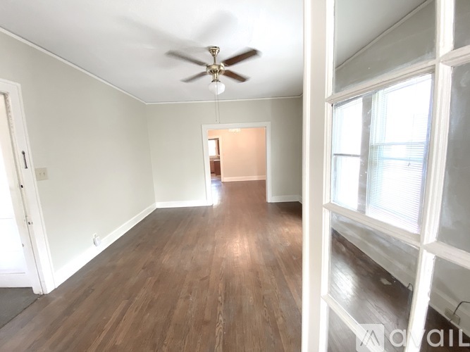 A room with a ceiling fan and wooden flooring.