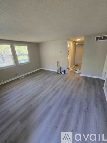 A room with wooden flooring and a window on the left side.