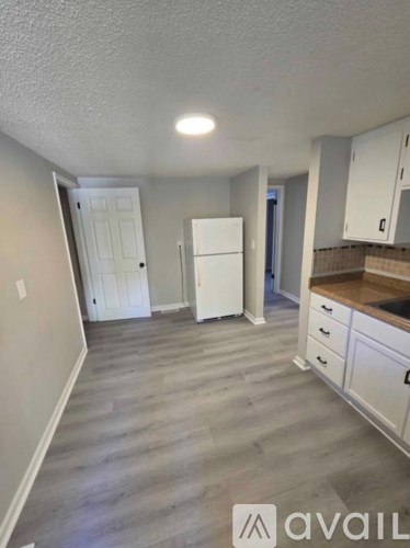A kitchen with white cabinets and a white fridge.