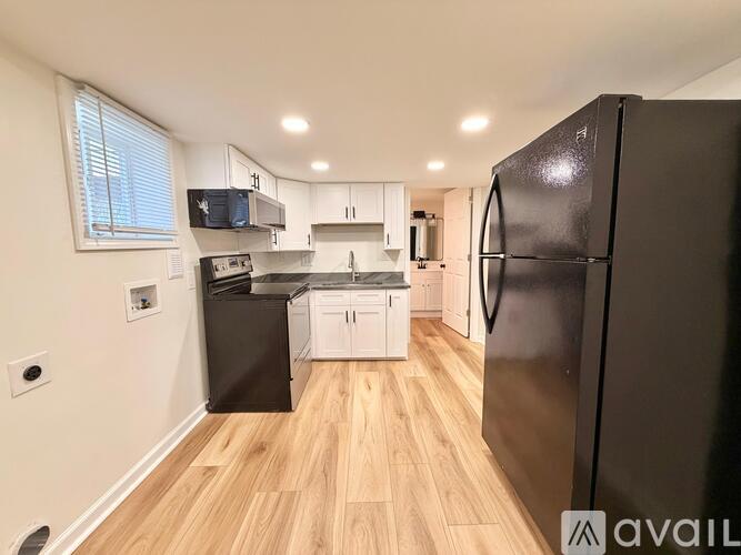 A kitchen with black appliances and wooden floors.