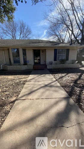 A house with a white front porch and a concrete walkway leading to it.