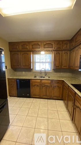A kitchen with wooden cabinets and a black dishwasher.
