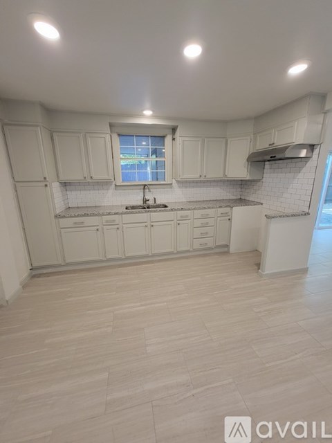 A kitchen with white cabinets and a window.