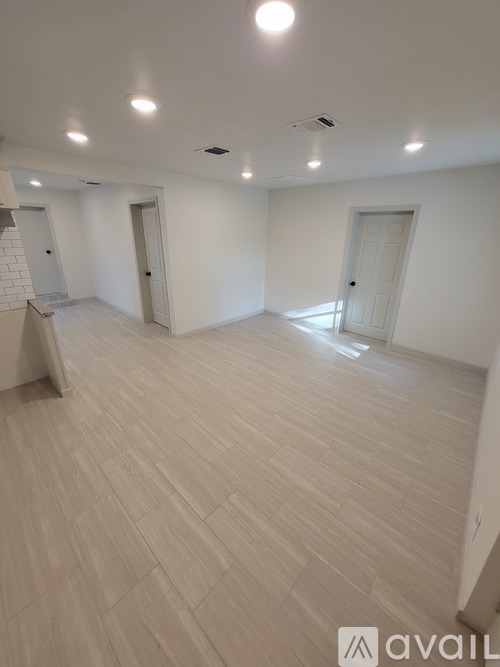 A spacious room with wooden flooring and white walls.