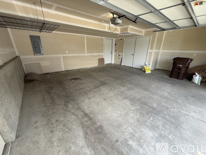 A large, empty room with concrete flooring and a ceiling with exposed beams and a light fixture.