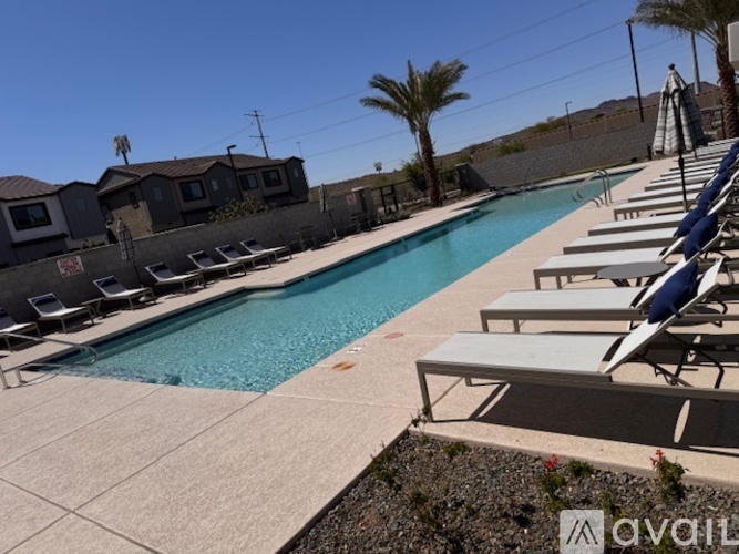 A pool with sun loungers and a clear blue sky.