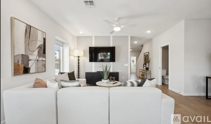 A modern living room with a white couch and a painting on the wall.
