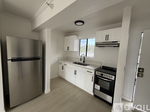 A kitchen with white cabinets and a stainless steel refrigerator.