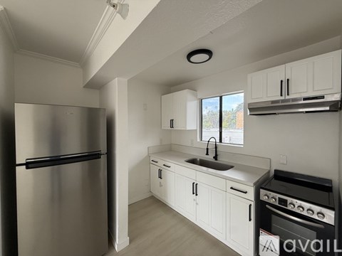 A kitchen with white cabinets and a stainless steel refrigerator.