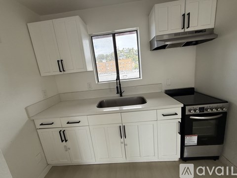 A kitchen with white cabinets and a window overlooking a street.