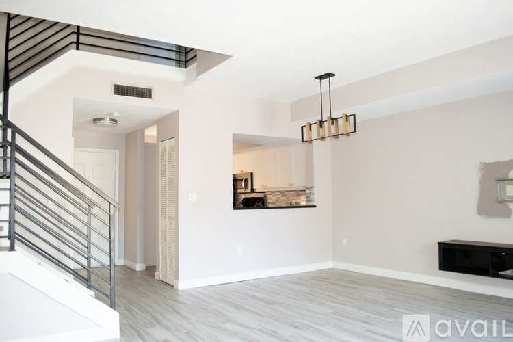 A modern interior space with a staircase on the left and a chandelier hanging from the ceiling.