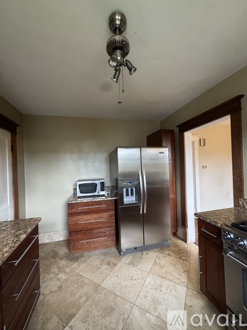 A kitchen with a stainless steel refrigerator and a microwave on top of a wooden cabinet.