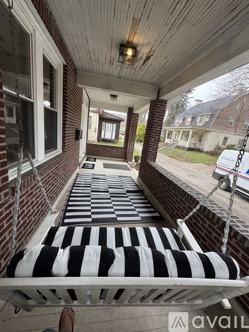A black and white striped bench is on a porch.