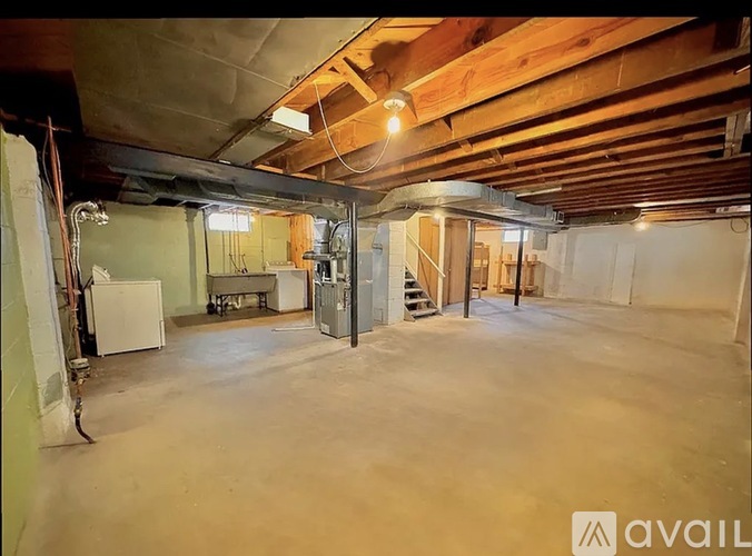 A spacious basement with a concrete floor and exposed wooden beams.