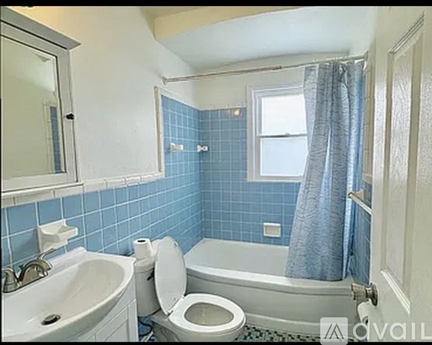 A bathroom with blue tiles and a white toilet.