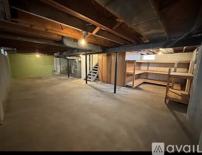 A large empty room with wooden beams on the ceiling and a ladder in the corner.