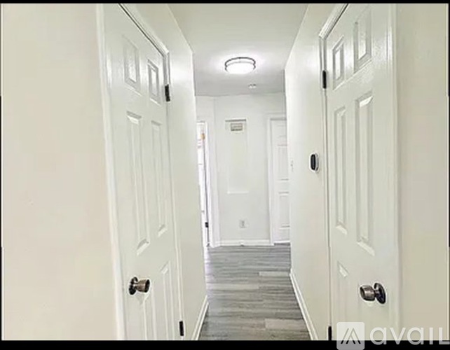 A hallway with white doors and a wooden floor.