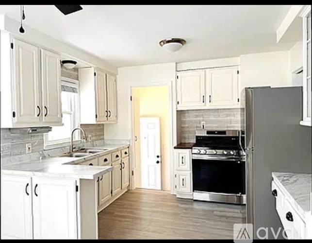 A kitchen with white cabinets and a black refrigerator.