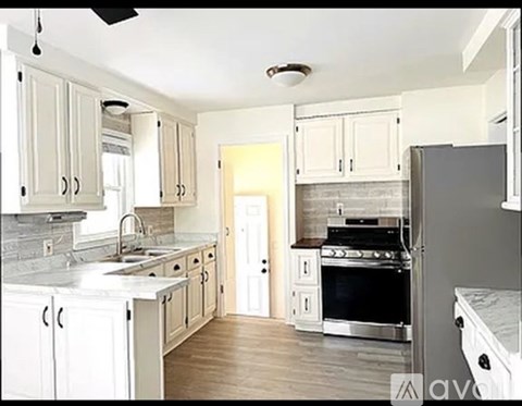 A kitchen with white cabinets and a black refrigerator.