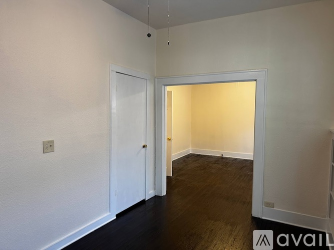 A room with a white door and a white wall with a light switch.