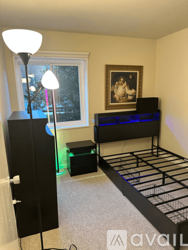 A bedroom with a bed, nightstand, and a painting on the wall.