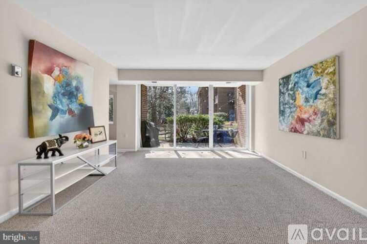 A spacious room with a grey carpet and two large paintings on the wall.
