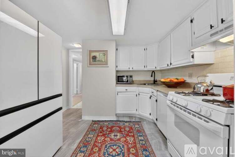 A kitchen with white cabinets and a red rug on the floor.