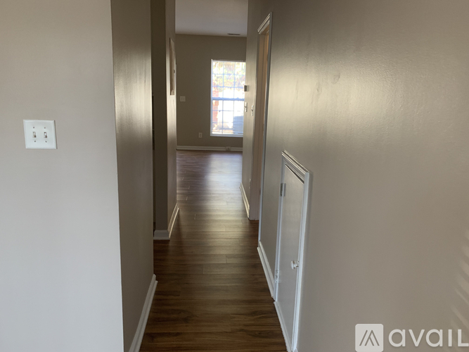 A long hallway with wood floors and white walls.