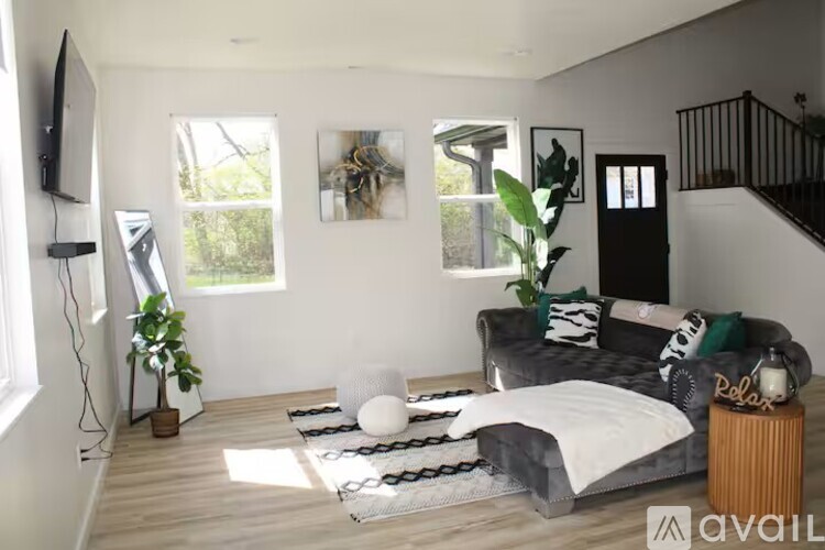 A living room with a grey couch, a white floor lamp, and a TV on the wall.