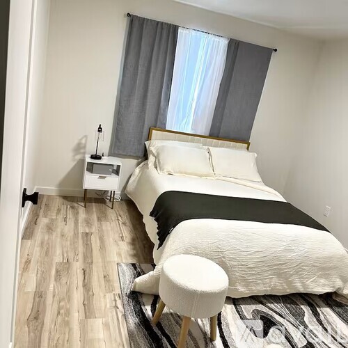 A bedroom with a large bed and a small nightstand.