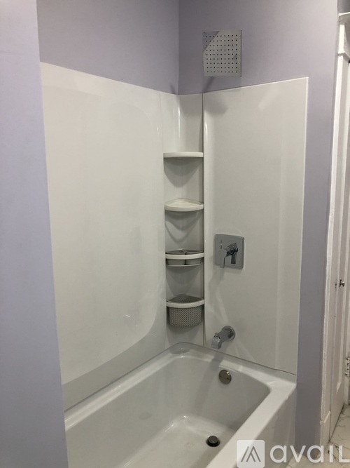 A white bathtub with a shower head and a shelf.