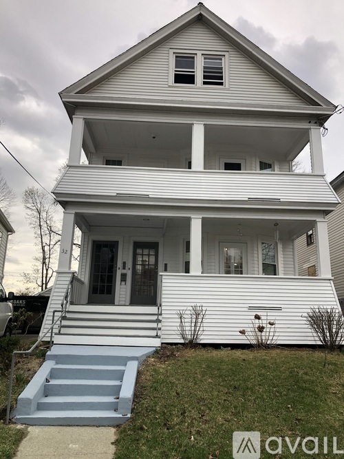 A two-story house with a front porch and stairs leading up to the entrance.
