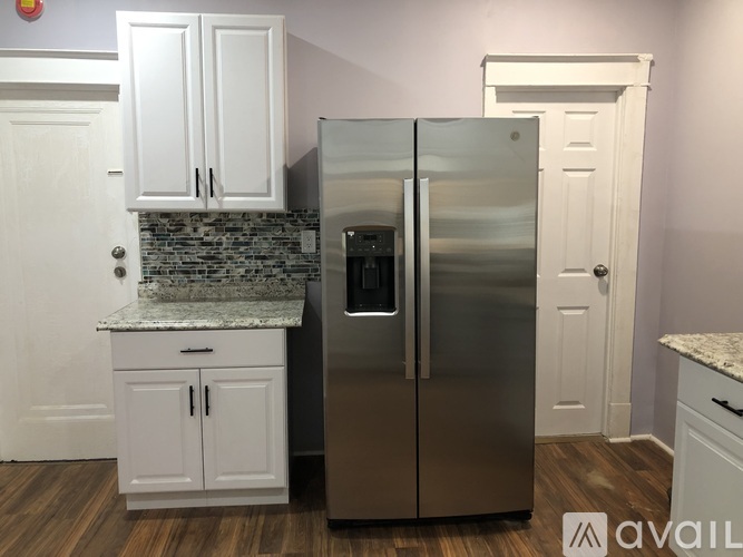 A kitchen with a stainless steel refrigerator and white cabinets.