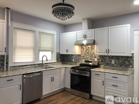 A kitchen with white cabinets and a stone backsplash.