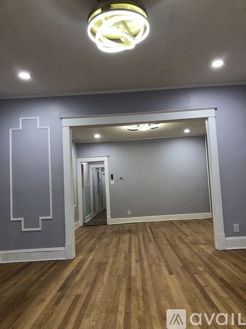 A room with wooden floors and a grey wall with a white design on it.