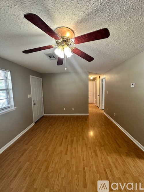 A room with a ceiling fan and wooden flooring.