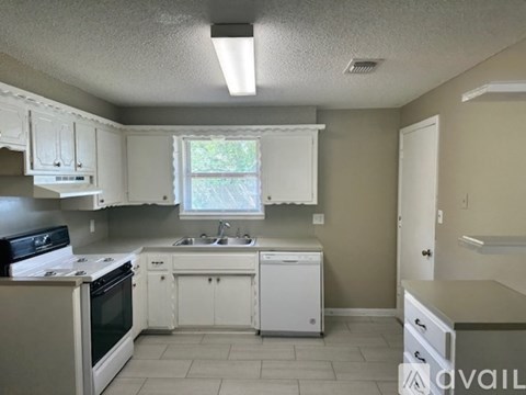 A kitchen with white cabinets and appliances.