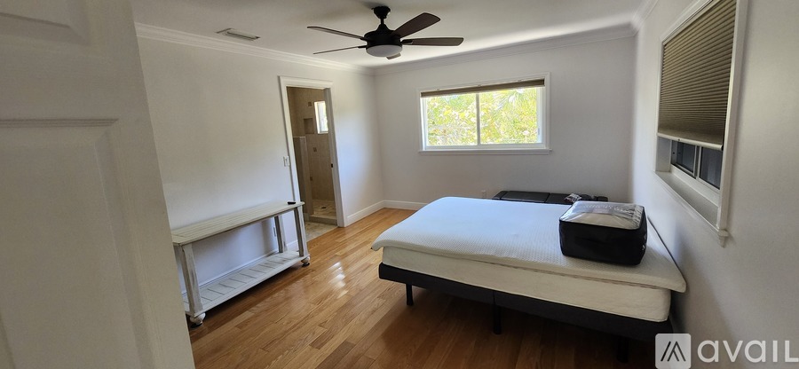 A bedroom with a bed, a ceiling fan, and a window.