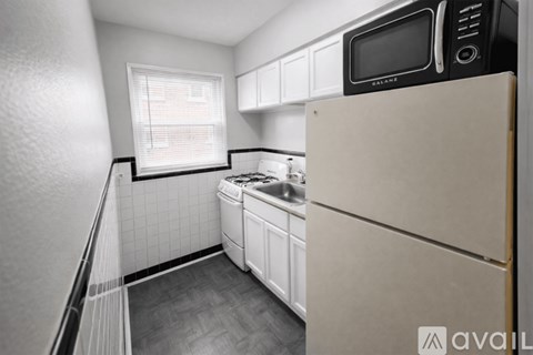 A kitchen with a white fridge and a black microwave.