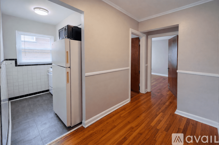 A kitchen with a white fridge and wooden floors.