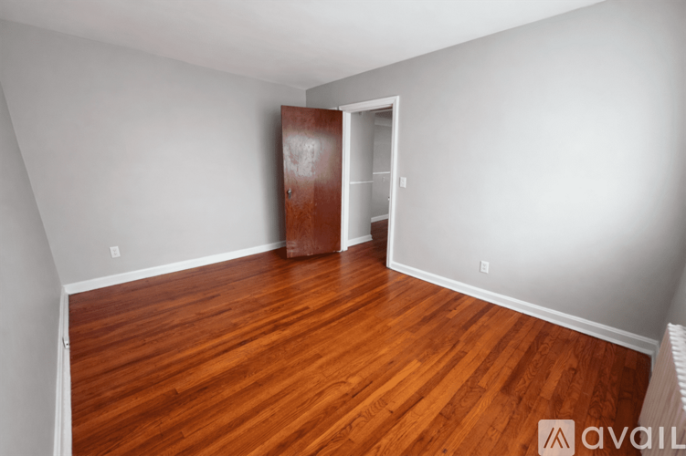 A room with wooden floors and a door on the left.