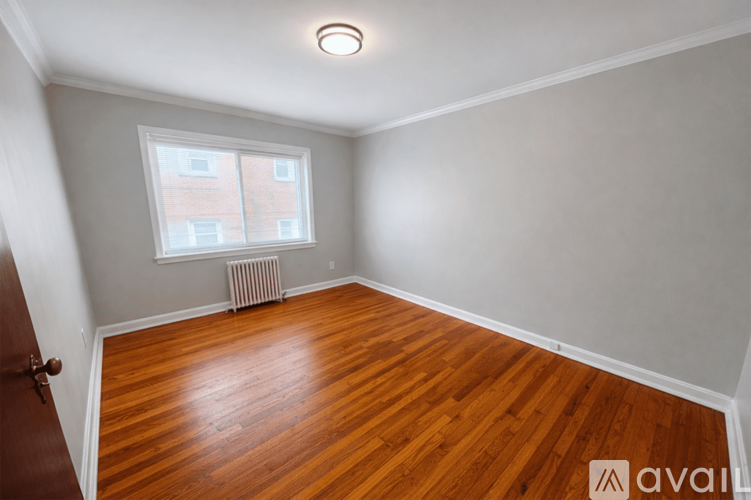 A room with wooden flooring and a window with a radiator beneath it.