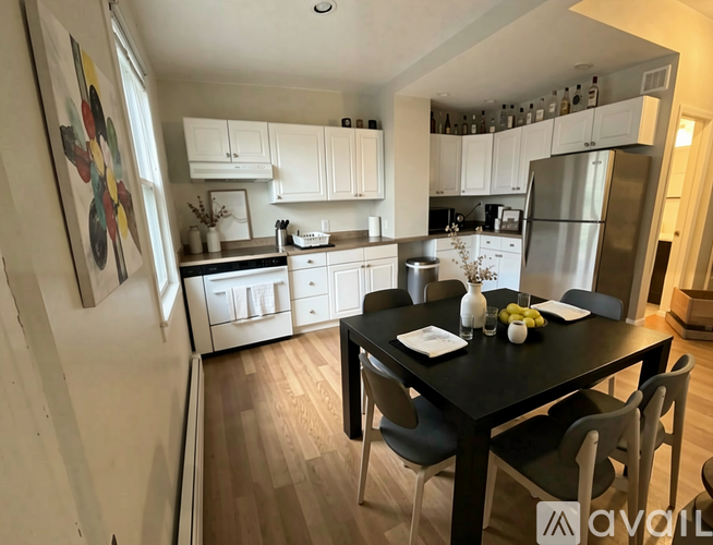 A kitchen with a table and chairs in the foreground and a refrigerator in the background.