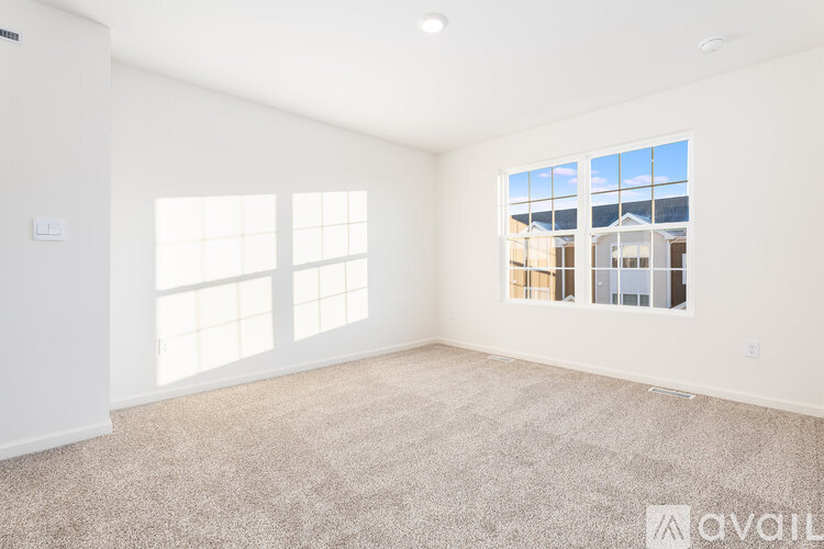 A spacious empty room with a large window and carpeted floor.