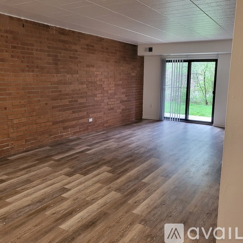 A room with wooden flooring and a brick wall.